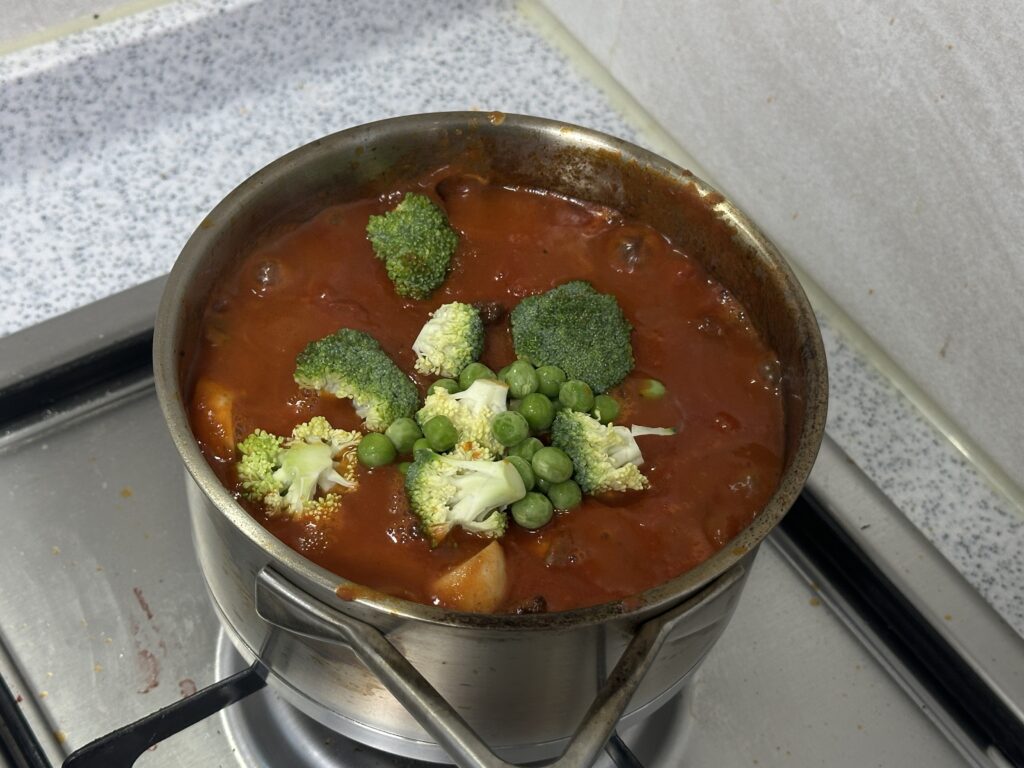 토마토 스프에 브로콜리와 완두콩을 넣고 끓이는 모습
